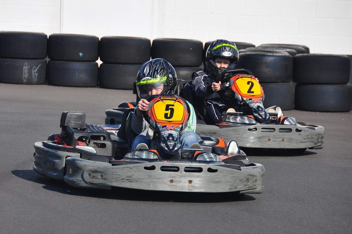 Deux jeunes pilotes dans des kartings numérotés 5 et 2 sur piste
