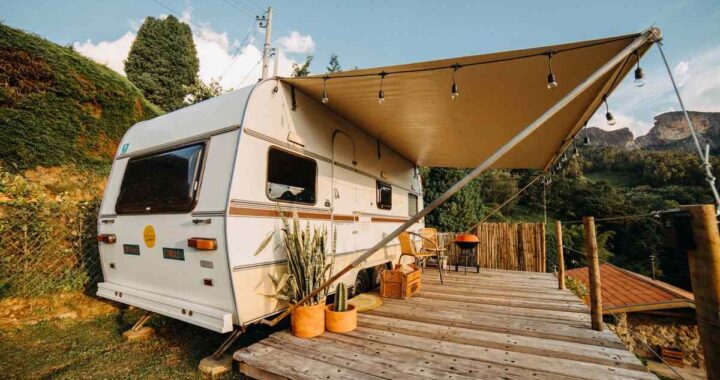 Caravelle blanche avec auvent sur terrasse en bois, jardin et montagnes sous ciel clair