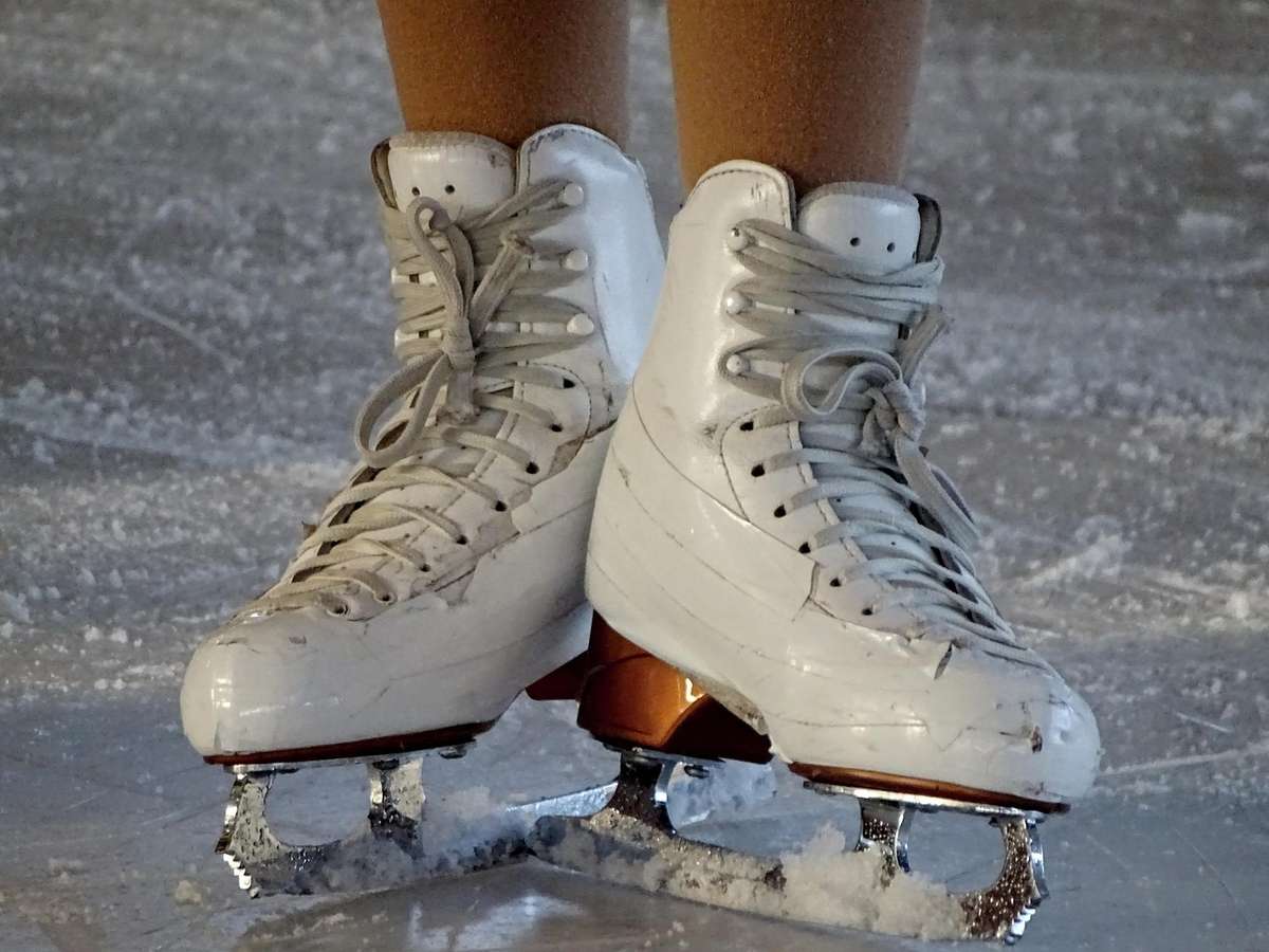 Des patins à glace blancs sur les pieds, sur une patinoire glacée Des patins à glace blancs sur les pieds, sur une patinoire glacée