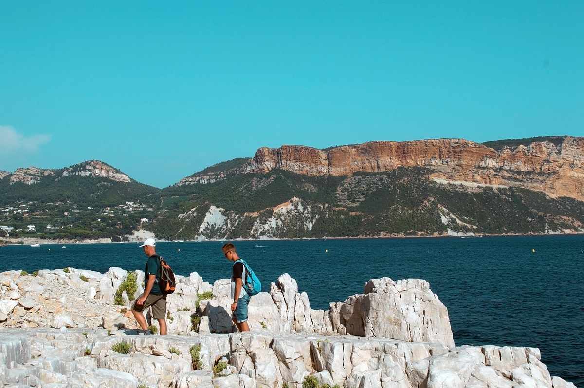Deux personnes avec sacs à dos marchent sur rochers près de la mer Deux personnes avec sacs à dos marchent sur rochers près de la mer