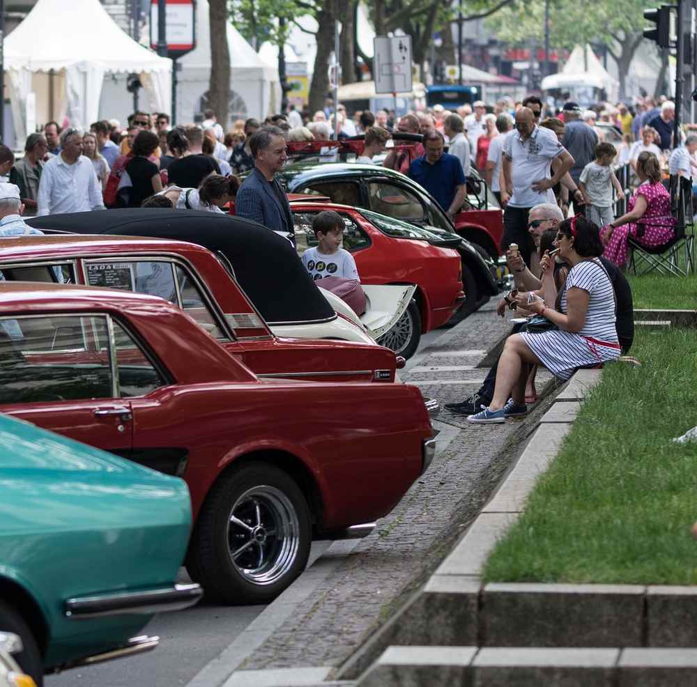 Une rangée de voitures anciennes avec des spectateurs sur le trottoir Une rangée de voitures anciennes avec des spectateurs sur le trottoir