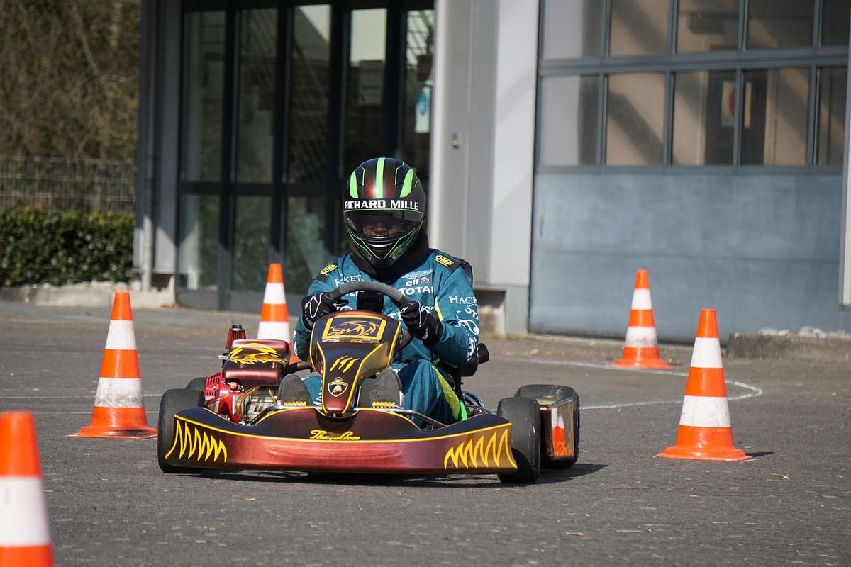 Un pilote en karting navigue entre cônes orange sur asphalte Un pilote en karting navigue entre cônes orange sur asphalte