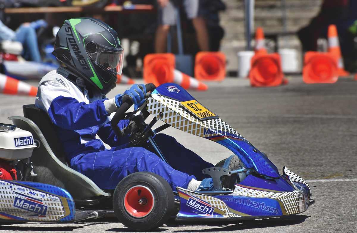 Un coureur en combinaison bleue pilote un kart bleu sur circuit Un coureur en combinaison bleue pilote un kart bleu sur circuit